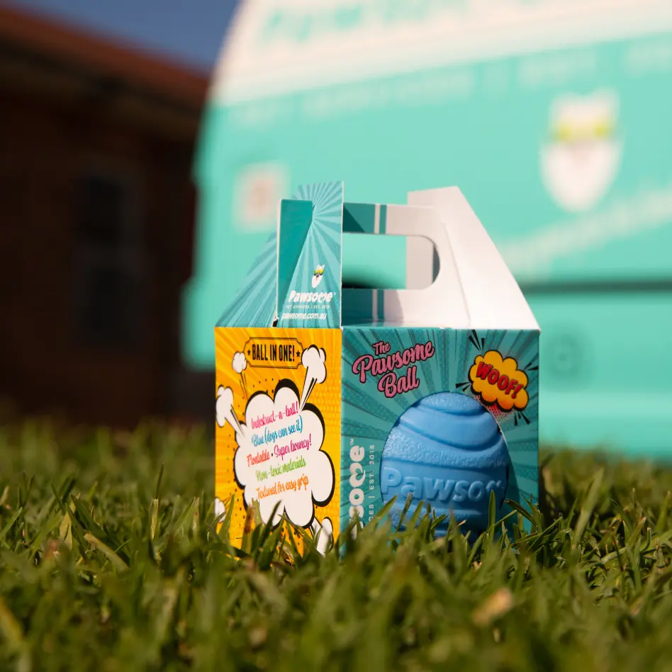 The blue Pawsome Ball, a durable dog ball, sitting on bright green grass.